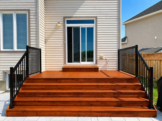 Freshly stained Ottawa deck steps with rich brown wood finish and black aluminum railings