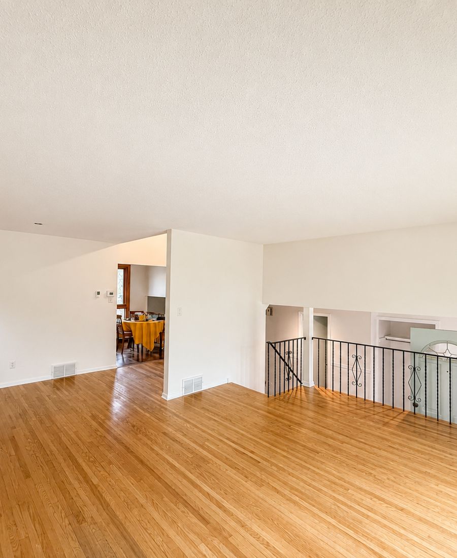 Bright open-concept living area with freshly painted warm white walls, textured ceiling, and refinished oak hardwood floors in New Edinburgh