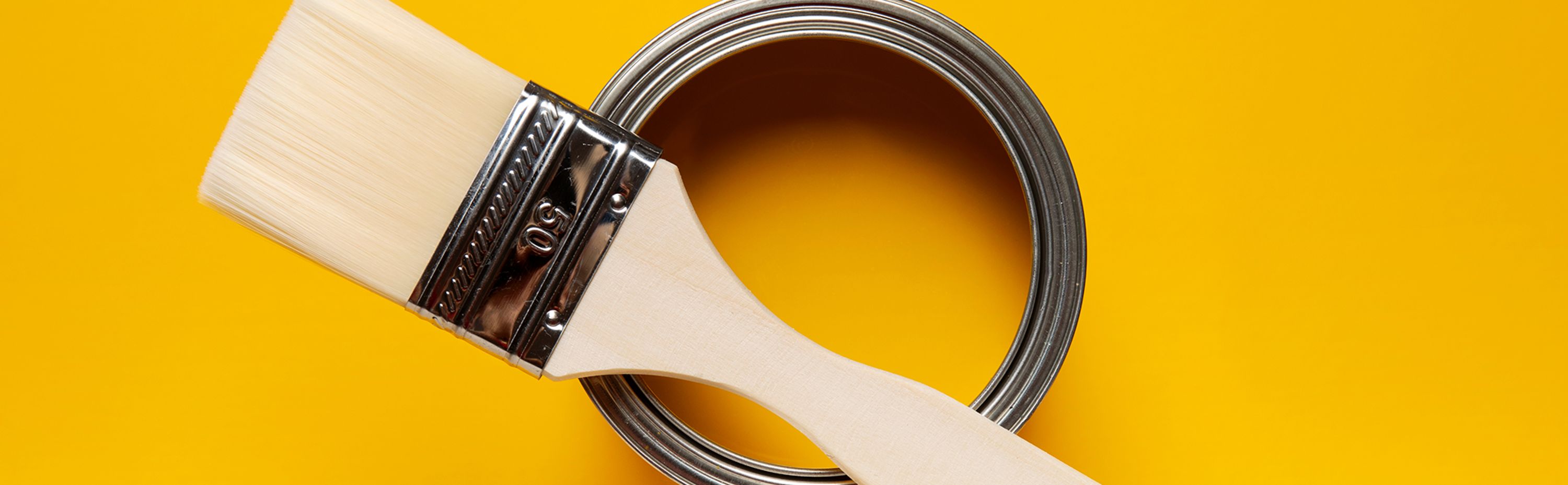 yellow background and yellow paint can with brush sitting on top